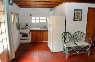 a kitchen with a refrigerator and two chairs in it at LA TOMA Complejo de Montaña - Cabañas y Habitaciones en Hosteria in Mina Clavero