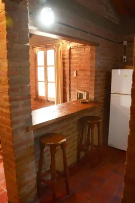 a kitchen with a counter with stools and a refrigerator at LA TOMA Complejo de Montaña - Cabañas y Habitaciones en Hosteria in Mina Clavero