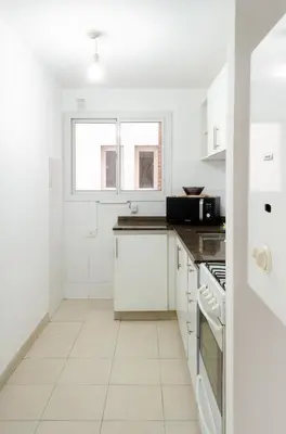 a white kitchen with white cabinets and a window at Apartamento Obispo Trejo IV by Lofty in Cordoba