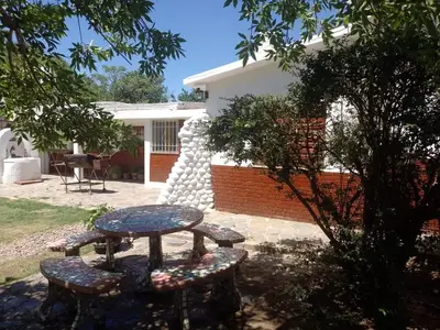 a table and two benches in a yard at El Chaparral Villa Dolores Traslasierra 2 in Piedra Pintada