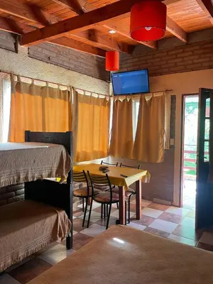 a room with two beds and a table and a tv at Altos del Mayu Cabañas - Alojamiento in San Antonio de Arredondo