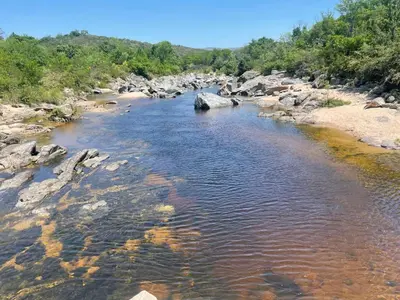 a river with rocks and trees in the background at Altos del Mayu Cabañas - Alojamiento in San Antonio de Arredondo