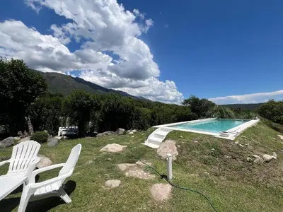 a swimming pool with two white chairs next to it at Casita siempre verde in Los Hornillos
