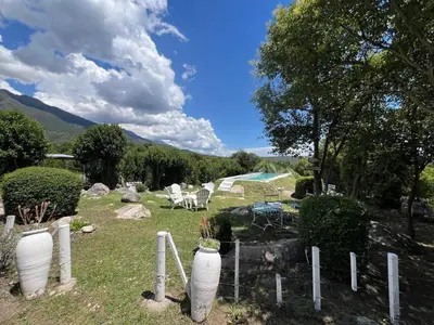 a garden with white vases and chairs and a fence at Casita siempre verde in Los Hornillos