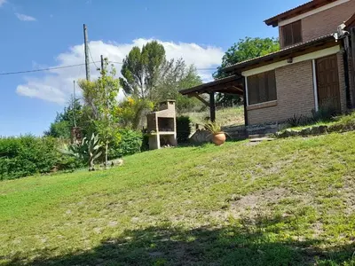 a house on a grassy hill next to a house at Suricabanias in Villa Yacanto