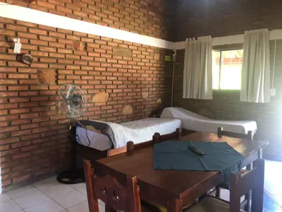 a room with two beds and a table at Complejo La Morena in Mina Clavero
