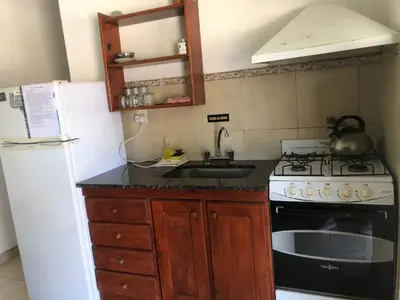 a kitchen with a stove and a sink and a refrigerator at Complejo La Morena in Mina Clavero