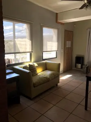 a living room with a couch and two windows at La Osadia Cabañas y Suites Solo Adultos in Mina Clavero