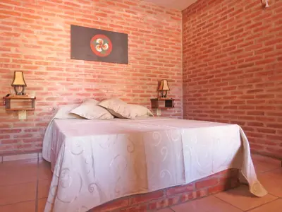 a bedroom with a white bed with two lamps at La Osadia Cabañas y Suites Solo Adultos in Mina Clavero