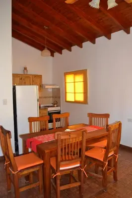 a kitchen with a wooden table with chairs and a refrigerator at Aguas Mornas Cabañas in Mina Clavero