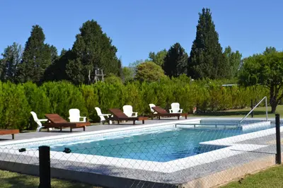 a swimming pool with lounge chairs next to a field at Aguas Mornas Cabañas in Mina Clavero