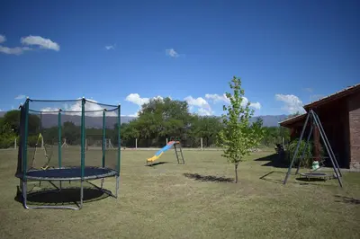 a playground with three swings and a slide at Complejo Sol Serrano in Mina Clavero