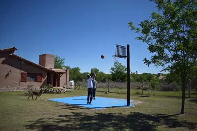 a man throwing a frisbee at a basketball hoop with a dog at Complejo Sol Serrano in Mina Clavero