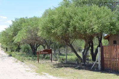 a sign on the side of a road next to trees at Complejo Sol Serrano in Mina Clavero