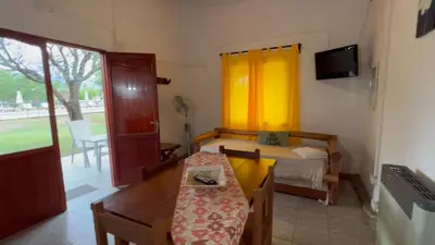 a small room with a table and a bed and a window at Complejo Sol Serrano in Mina Clavero