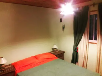 a bedroom with a bed with red sheets and a window at Cabañas de Campo in Santa María