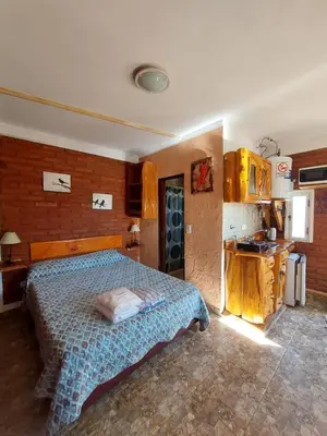 a bedroom with a large bed and a kitchen at Cerros Azules in Trapiche