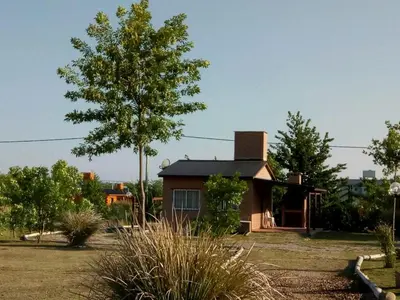 a small house in a yard with a tree at Cabañas Hilario in Los Reartes