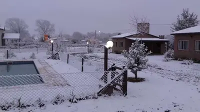 a yard covered in snow with a fence and lights at Cabañas Hilario in Los Reartes