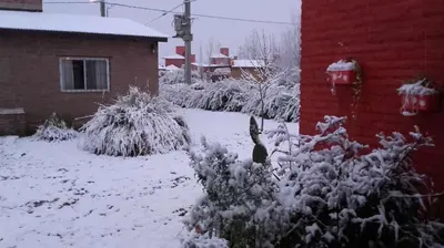 a yard covered in snow next to a house at Cabañas Hilario in Los Reartes
