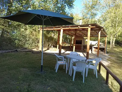 a table and chairs under an umbrella in the grass at siete colores in Santa Rosa de Calamuchita