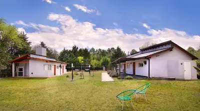 a yard with two chairs in front of two buildings at Altos del Rio (Solo parejas) in Los Reartes