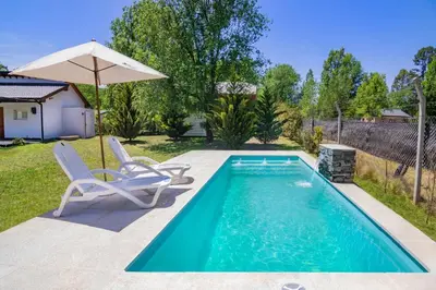 a swimming pool with two chairs and an umbrella at Altos del Rio (Solo parejas) in Los Reartes