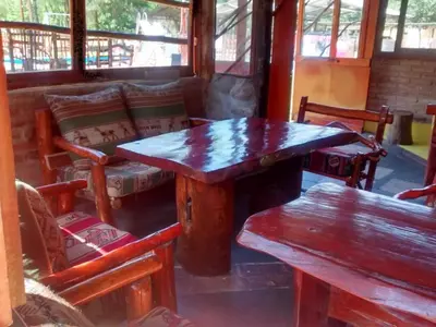 a wooden table and benches in a room with windows at Posada del Tata in Nono