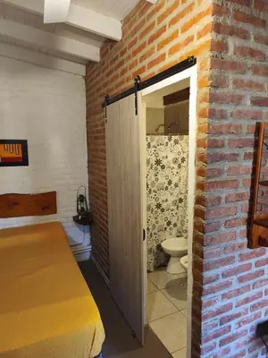 a bedroom with a bed and a brick wall at Posada del Tata in Nono