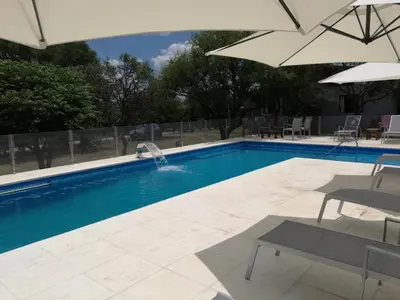 a swimming pool with an umbrella and a fountain at Casas Acrux in Nono