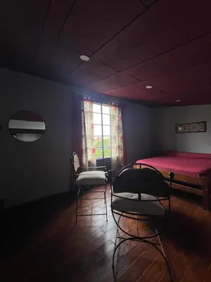 a room with two beds and chairs and a window at Posada Altos Del Consuelo in Nono
