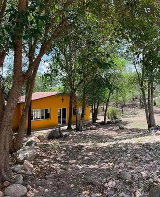 a yellow house with trees in front of it at Posada Altos Del Consuelo in Nono