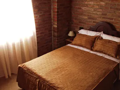 a bedroom with a large bed with a brick wall at Cabañas del Dique Frente al Lago in Villa del Dique