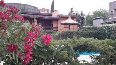 a house with a garden with pink flowers at Cabañas del Dique Frente al Lago in Villa del Dique