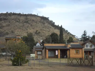 a house with a hill in the background at Cabañas del Dique Frente al Lago in Villa del Dique