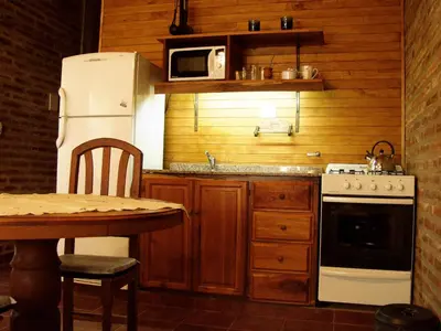 a kitchen with a white refrigerator and a table at Cabañas del Dique Frente al Lago in Villa del Dique