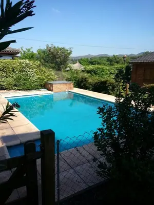 a large blue swimming pool with a fence at Cabañas del Dique Frente al Lago in Villa del Dique