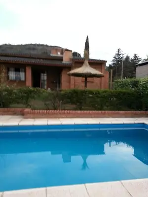 a blue swimming pool in front of a house at Cabañas del Dique Frente al Lago in Villa del Dique