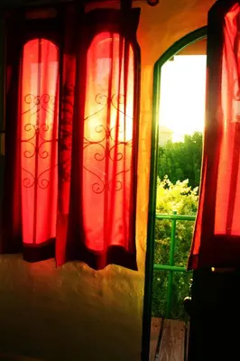 a window with red curtains and a view of a yard at Villa Leandro in Mina Clavero