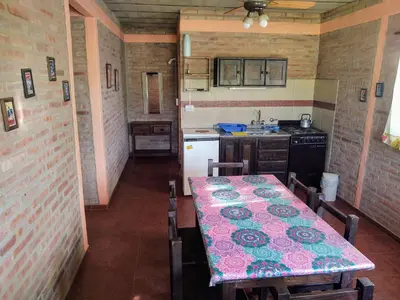 a kitchen with a table and a kitchen with a table and chairs at Cabañas Don Juan in Mina Clavero