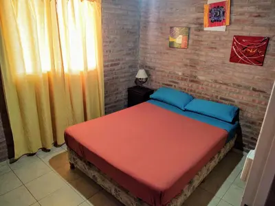 a bedroom with a bed with a red and blue blanket at Cabañas Don Juan in Mina Clavero