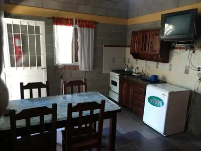 a kitchen with a table and a white refrigerator at Cabañas Don Juan in Mina Clavero