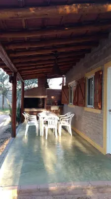 a patio with white chairs and a table and a piano at Cabañas Don Juan in Mina Clavero