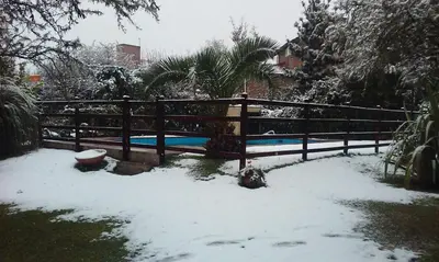 a fence with snow on the ground next to a pool at Luna Azul in Merlo