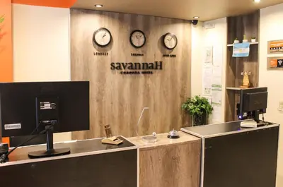 a reception desk with clocks on a wall at Savannah Cordoba Hotel in Cordoba