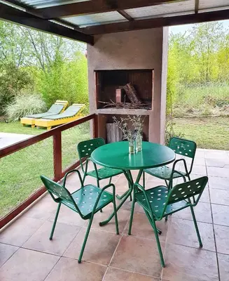 a green table and chairs on a patio with a fireplace at Cabaña Josefina in Los Reartes
