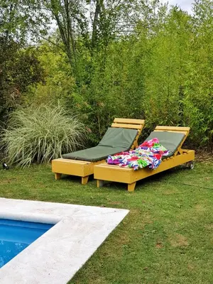 two beds sitting on the grass next to a pool at Cabaña Josefina in Los Reartes