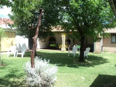 a yard with white chairs and a table and trees at La Nona in Villa Cura Brochero
