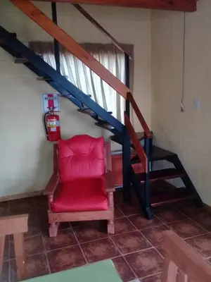 a red chair in a room with a staircase at Cabañas Villa del Mirador in Bialet Massé