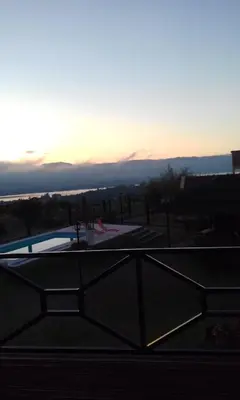 a view of a swimming pool with the sunset in the background at Cabañas Villa del Mirador in Bialet Massé